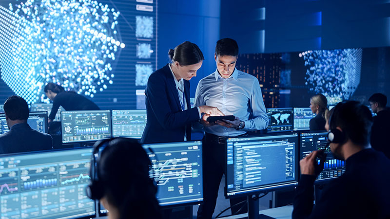 Two professionals reviewing live dashboards in an operations room
